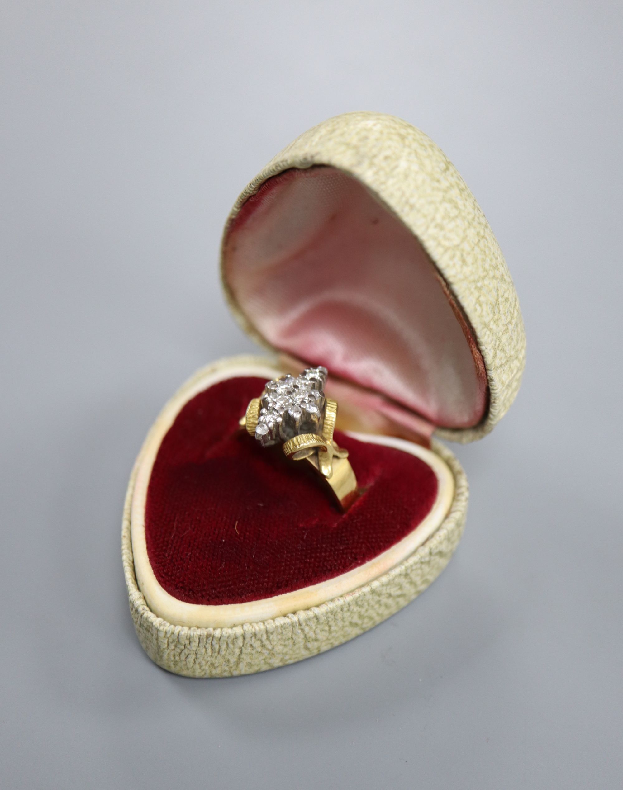 An 18ct and diamond cluster dress ring, in a raised setting, size Q/R, gross 5.9 grams.